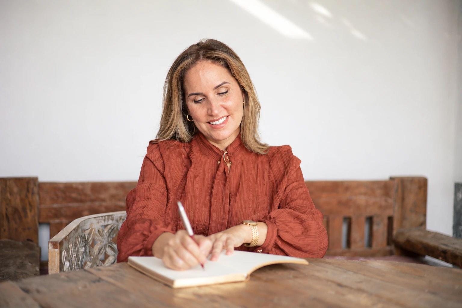Fayna Curbelo escribiendo en una libreta sobre una mesa rústica de madera.